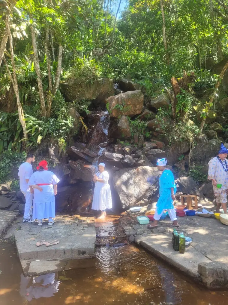 Yalorixá Cigana de pés na água, rezando na cachoeira junto com irmãos de axé vestidos de branco